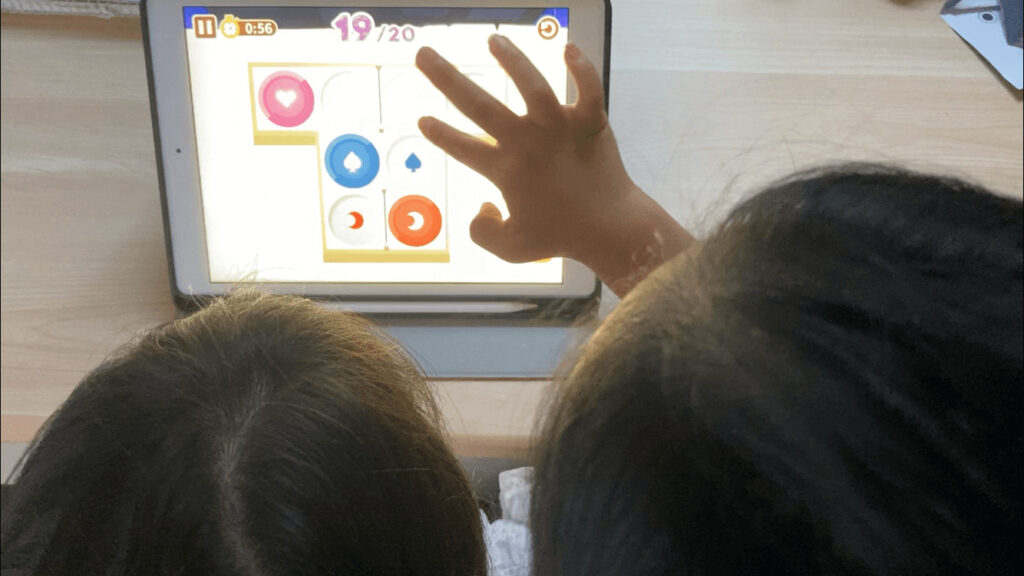 2人の子供が、iPadをみている写真。iPadの画面には、ワンダーラボ体験版アプリのバベロンプラスが表示されている。右の子供が画面をタップしている様子。