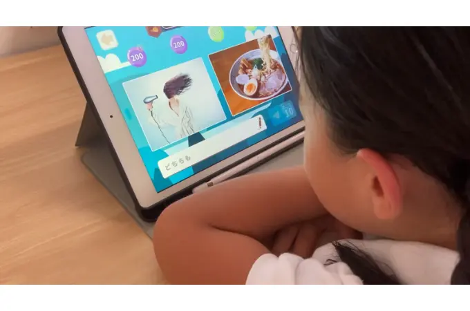 5才の女の子がiPadでワンダーボックスをしている。タブレットの画面にはそっくりさがしの問題が表示されている。