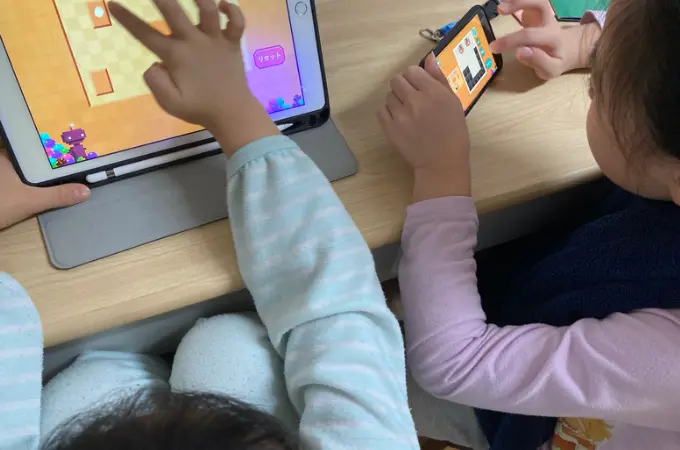 ５才と８才の女の子が、並んでワンダーボックスのアプリで遊んでいる写真。